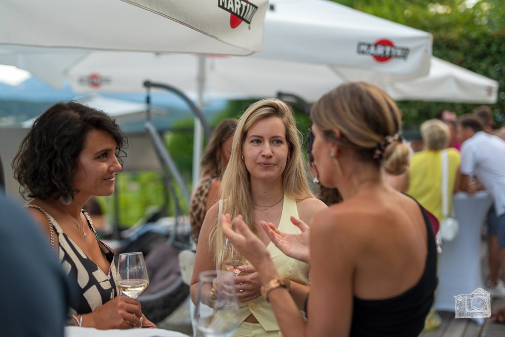 Junge Damen unterhalten sich auf einem Event mit einem Glas Wein in der Hand.