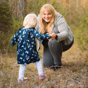 kleines Mädchen läuft auf ihre Mutter zu, die mit offenen Armen auf sie wartet.